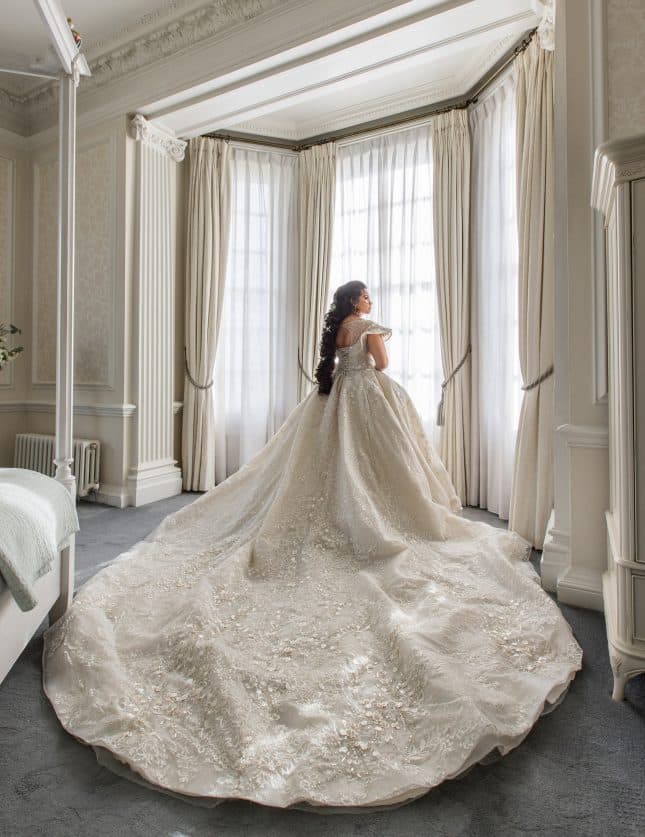 Bride with stunning wedding dress train in bedroom